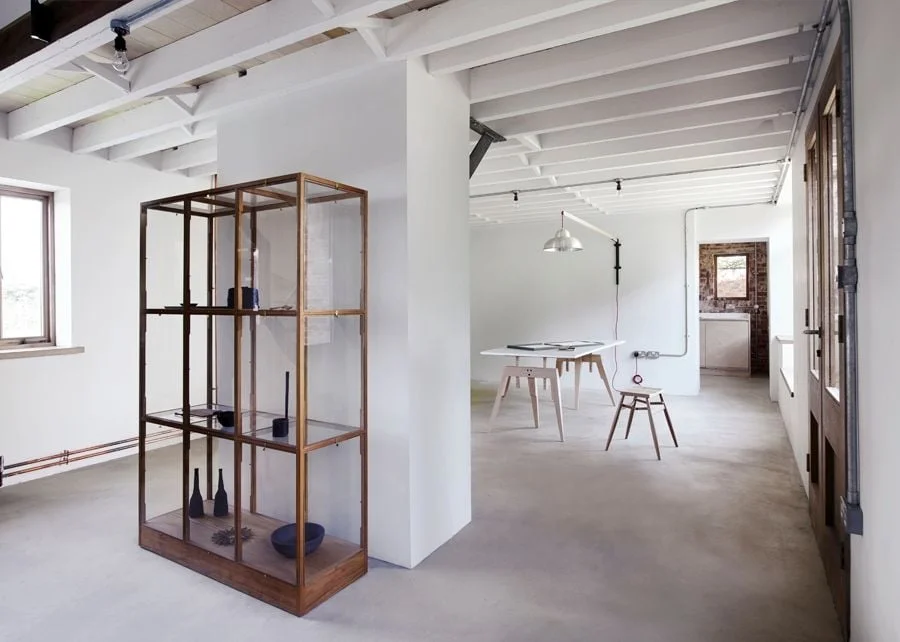 Espace professionnel moderne minimaliste avec mobilier en bois clair et sol béton poli.