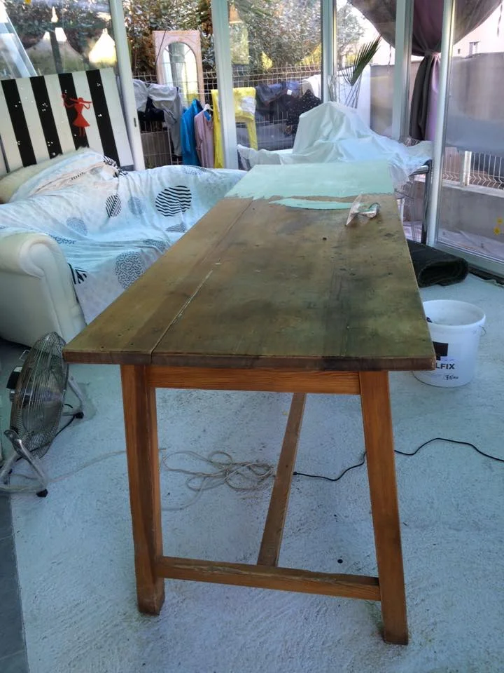 Application d'un enduit décoratif vert clair sur une surface de travail dans un chantier de rénovation.