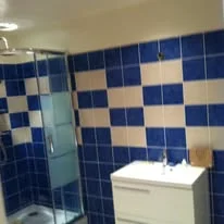 Exemple de rénovation complète de salle de bain moderne avec carrelage mural bleu et blanc en damier, douche vitrée et meuble vasque.